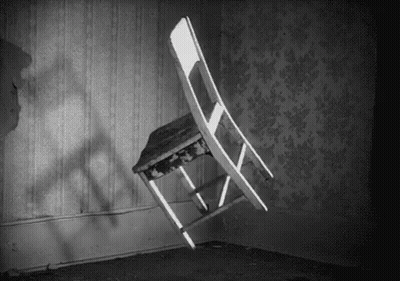 A Black And White Photo Of A Chair That Is Flying Through The Air In A Room . GIF