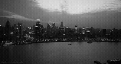 A Black And White Photo Of A City Skyline And A Lake GIF