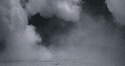 A Black And White Photo Of A Cloudy Sky With A Plane Flying Through It . GIF