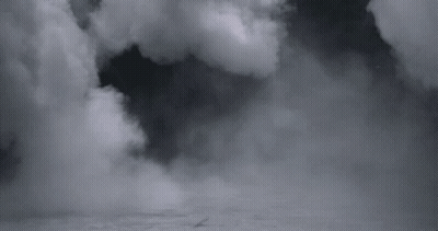 A Black And White Photo Of A Cloudy Sky With A Plane Flying Through It . GIF