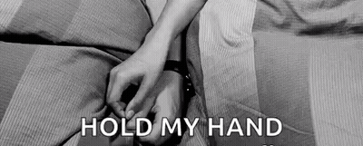 A Black And White Photo Of A Couple Holding Hands On A Bed With The Words `` Hold My Hand '' . GIF