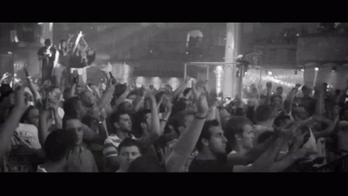 A Black And White Photo Of A Crowd At A Party With Their Hands In The Air GIF