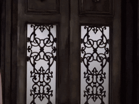 A Black And White Photo Of A Door With A Wrought Iron Design On It GIF