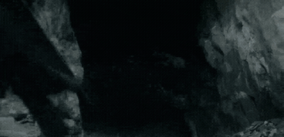 A Black And White Photo Of A Dragon Flying Over A Rocky Hillside . GIF