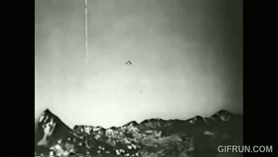 A Black And White Photo Of A Flying Object Over A Mountain Range . GIF