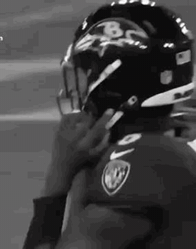 A Black And White Photo Of A Football Player Putting On His Helmet . GIF