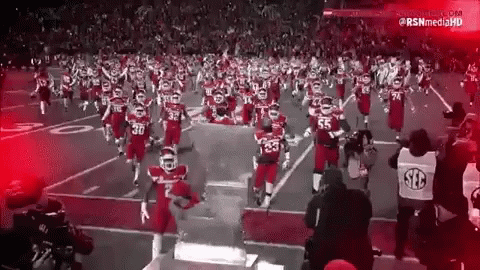 A Black And White Photo Of A Football Team Running On The Field GIF