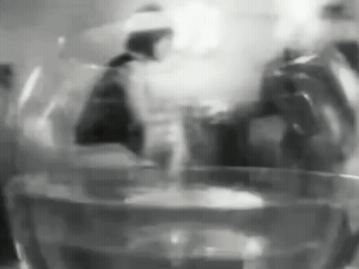 A Black And White Photo Of A Glass Of Water With A Person In The Background . GIF
