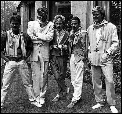 A Black And White Photo Of A Group Of Men Standing In Front Of A Building . GIF