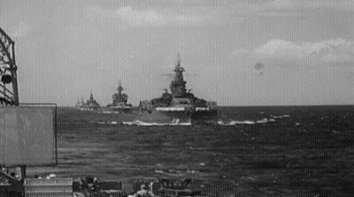 A Black And White Photo Of A Group Of Military Ships In The Ocean GIF