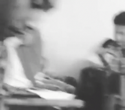 A Black And White Photo Of A Group Of People Sitting At A Table Using Their Phones . GIF