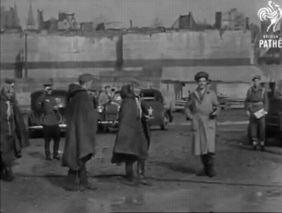 A Black And White Photo Of A Group Of People Standing In A Parking Lot With Pathe Written On The Bottom GIF