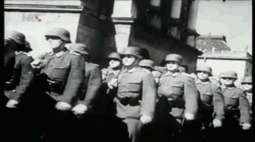 A Black And White Photo Of A Group Of Soldiers Marching In A Line GIF