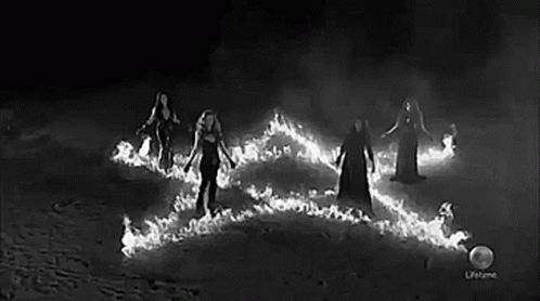 A Black And White Photo Of A Group Of Women Standing Around A Fire . GIF