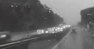 A Black And White Photo Of A Highway Covered In Rain . GIF