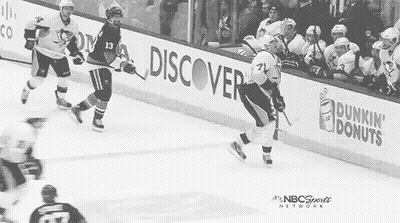 A Black And White Photo Of A Hockey Game With Dunkin Donuts Advertisements On The Sidelines . GIF