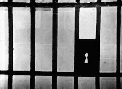 A Black And White Photo Of A Jail Cell With A Keyhole In The Middle GIF