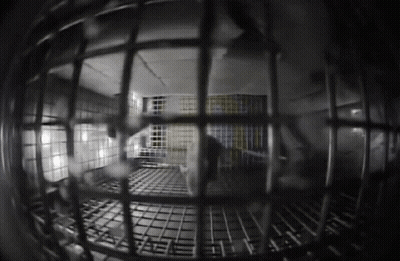 A Black And White Photo Of A Jail Cell With A Yellow And Blue Flag On The Wall GIF