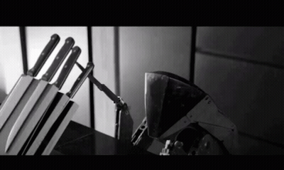 A Black And White Photo Of A Knife Block With Knives In It GIF