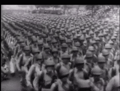 A Black And White Photo Of A Large Army Marching GIF
