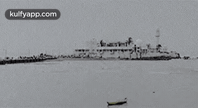 A Black And White Photo Of A Large Ship In The Ocean With A Boat In The Foreground . GIF