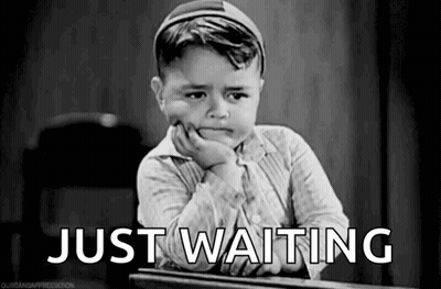 A Black And White Photo Of A Little Boy Sitting At A Desk With His Hand On His Chin And The Words `` Just Waiting '' . GIF