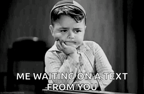 A Black And White Photo Of A Little Boy Sitting At A Desk With His Hand On His Chin . GIF