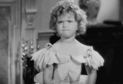 A Black And White Photo Of A Little Girl In A Dress Making A Funny Face . GIF