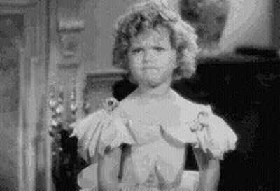 A Black And White Photo Of A Little Girl In A White Dress Making A Funny Face . GIF