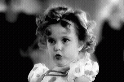 A Black And White Photo Of A Little Girl Wearing A Dress And A Headband . GIF