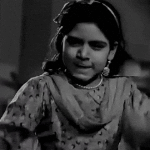 A Black And White Photo Of A Little Girl Wearing A Necklace And Earrings . GIF