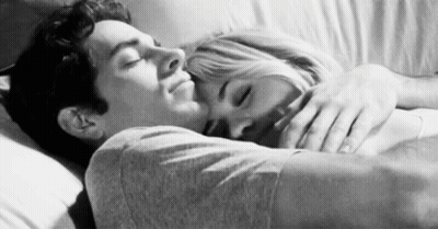 A Black And White Photo Of A Man And A Woman Hugging Each Other In Bed . GIF