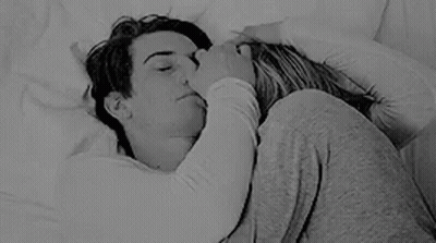 A Black And White Photo Of A Man And A Woman Hugging Each Other In Bed . GIF