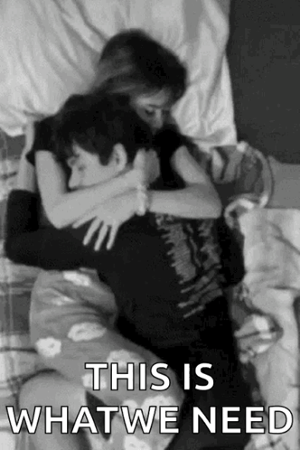A Black And White Photo Of A Man And A Woman Hugging Each Other On A Bed . GIF