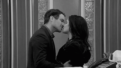 A Black And White Photo Of A Man And A Woman Kissing In An Office . GIF