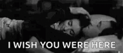 A Black And White Photo Of A Man And A Woman Laying In Bed With The Words `` I Wish You Were Here '' . GIF