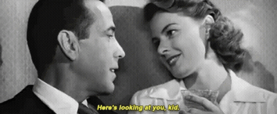 A Black And White Photo Of A Man And A Woman Looking At Each Other . GIF