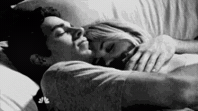 A Black And White Photo Of A Man And A Woman Sleeping In Bed . GIF