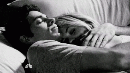 A Black And White Photo Of A Man And A Woman Sleeping In Bed . GIF