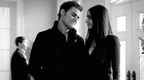 A Black And White Photo Of A Man And A Woman Standing Next To Each Other In A Room . GIF