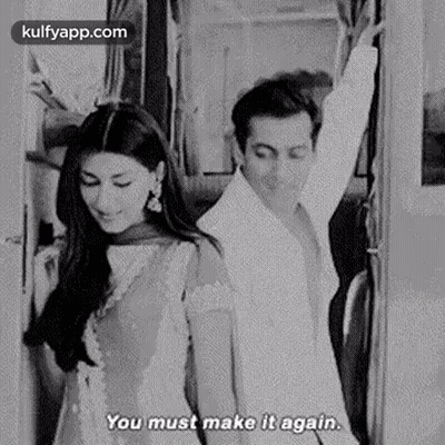 A Black And White Photo Of A Man And A Woman Standing Next To Each Other On A Train . GIF