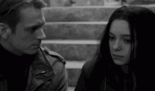 A Black And White Photo Of A Man And A Woman Standing Next To Each Other On Stairs . GIF