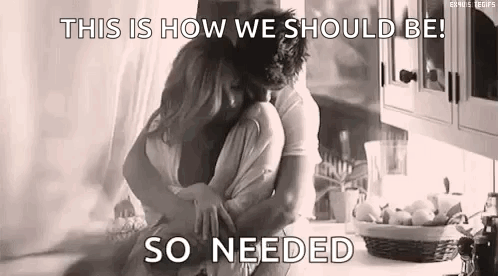A Black And White Photo Of A Man And Woman Hugging Each Other In A Kitchen . GIF