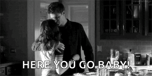 A Black And White Photo Of A Man And Woman Hugging Each Other In A Kitchen . GIF