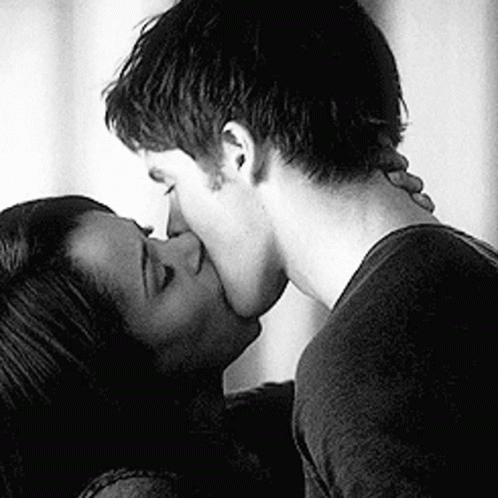 A Black And White Photo Of A Man And Woman Kissing Each Other . GIF