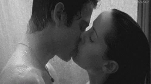 A Black And White Photo Of A Man And Woman Kissing In The Shower . GIF