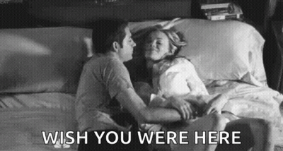 A Black And White Photo Of A Man And Woman Kissing On A Bed With The Words `` Wish You Were Here '' . GIF