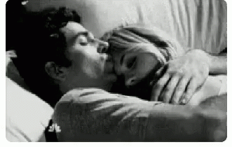 A Black And White Photo Of A Man And Woman Kissing While Laying In Bed . GIF