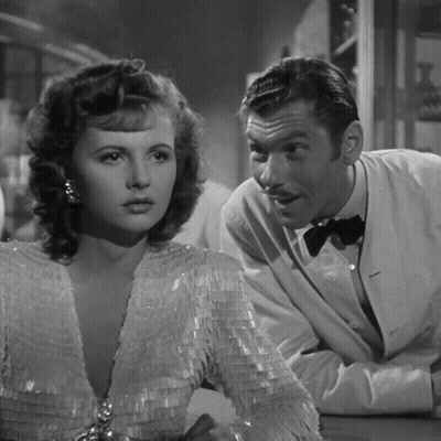 A Black And White Photo Of A Man And Woman Looking At Each Other GIF