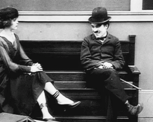 A Black And White Photo Of A Man And Woman Sitting On A Bench . GIF